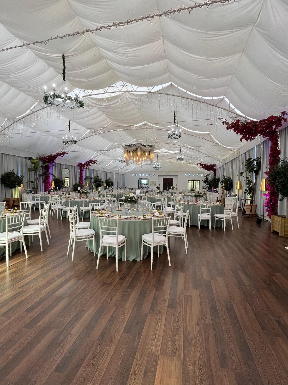 Vista general del salón de banquetes montado, con mesas redondas, suelo de madera y techo de tela drapeada
