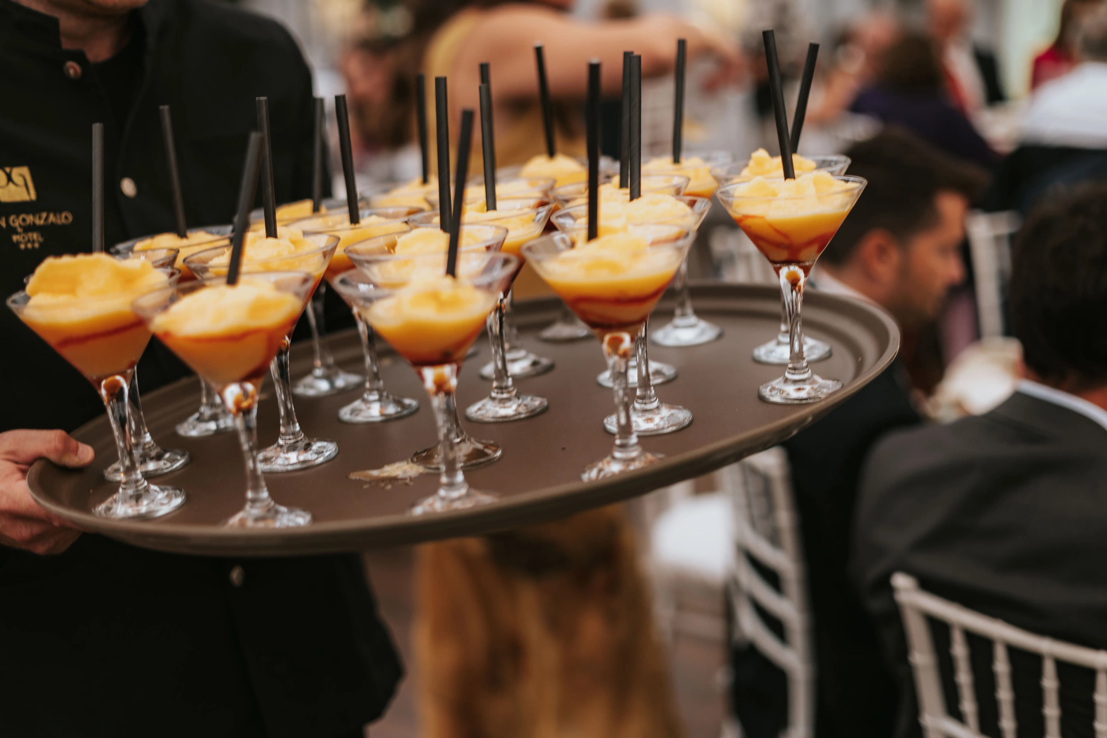 Camarero con bandeja de vasos de salmorejo servidos como aperitivo entre los invitados