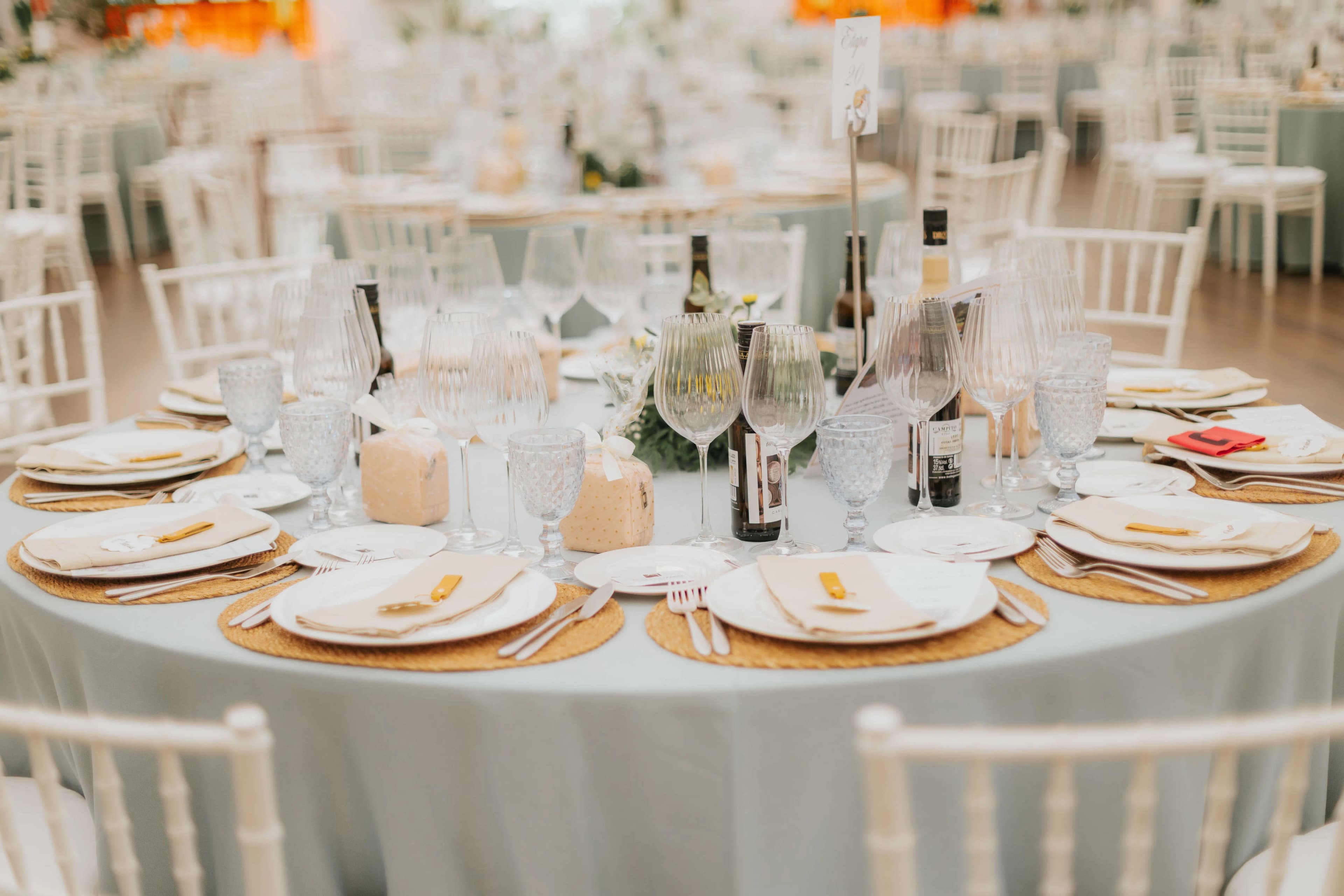 Detalle cenital de una mesa redonda vestida con vajilla, servilletas y botellas de vino de la tierra