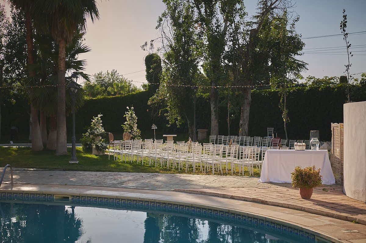 Piscina exterior del hotel rodeada de arbolado, al atardecer, con la zona ajardinada alrededor