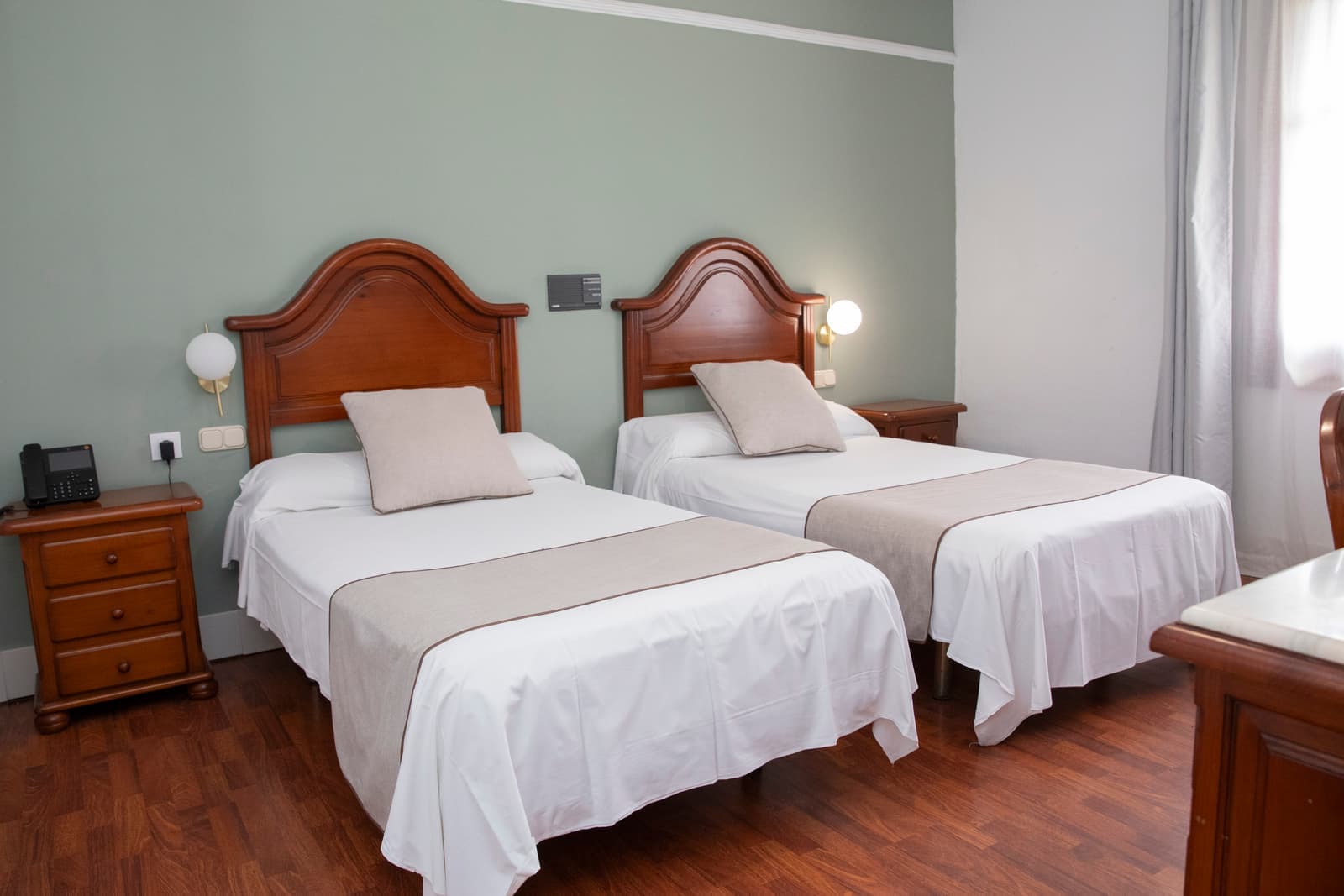 Habitación con dos camas individuales, cabeceros de madera torneada y suelo de tarima