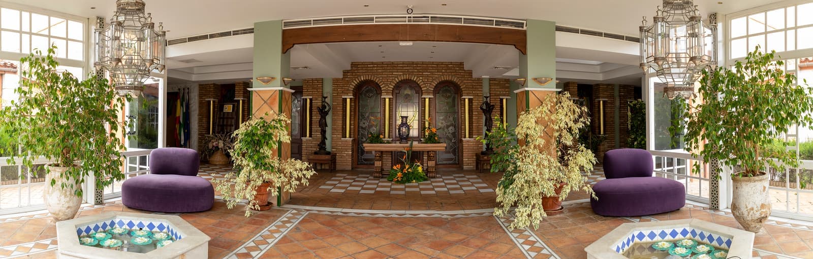 Patio interior del Hotel Don Gonzalo, con fuente de azulejos, plantas y arcos andalusíes